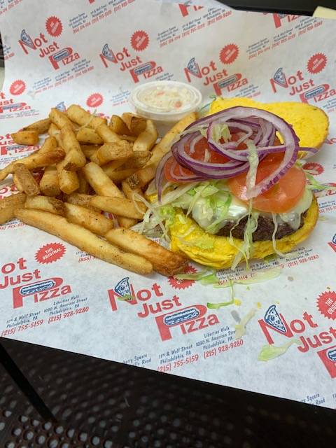 A burger with fries and onion on top of a piece of paper.