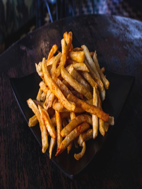 French fries on a black plate on a table.