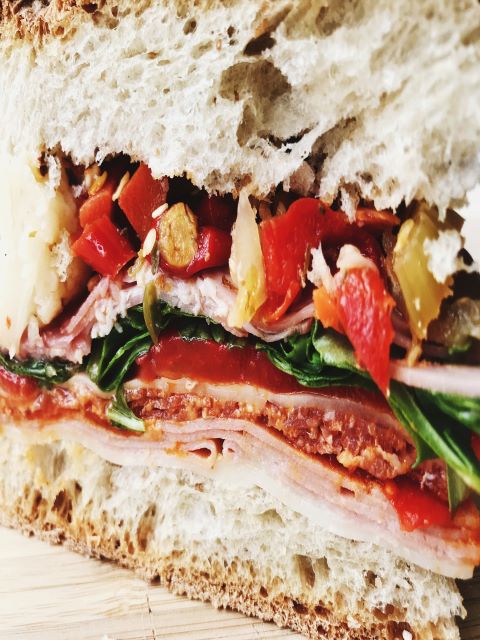 A sandwich with ham, peppers, and spinach.