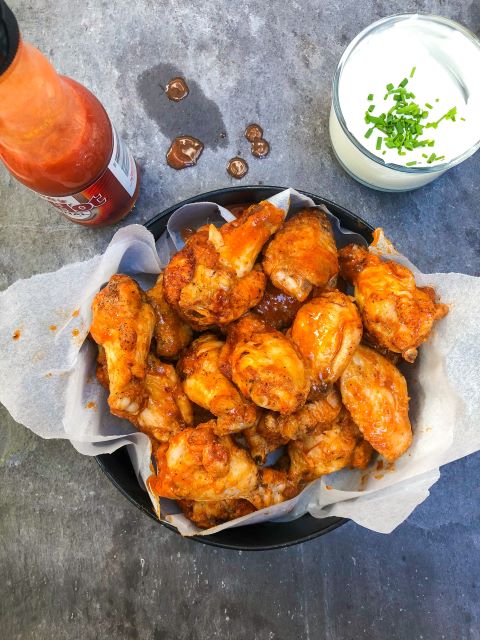 Bbq chicken wings in a bowl with dipping sauce.